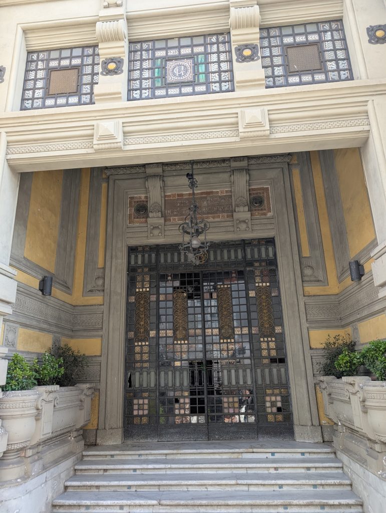 The grand facade of the Tettuccio Spa in Montecatini, featuring neoclassical columns and detailed stonework under a blue sky