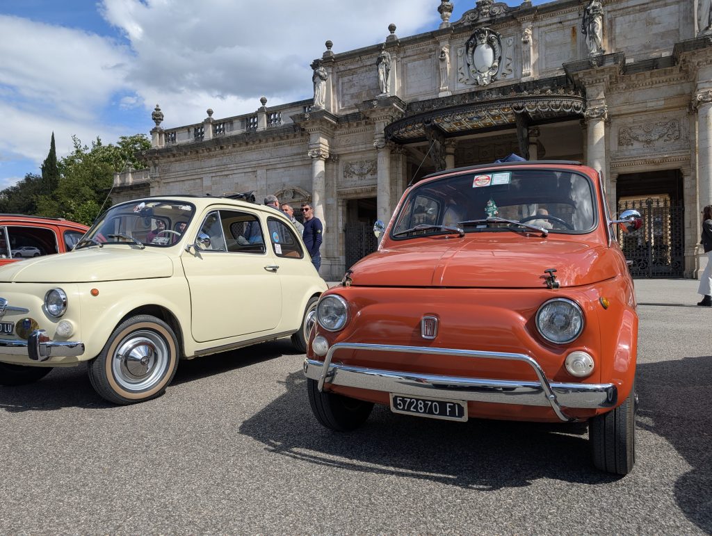  “A vintage red Fiat 500 parked on a narrow cobblestone street in an Italian hill town.